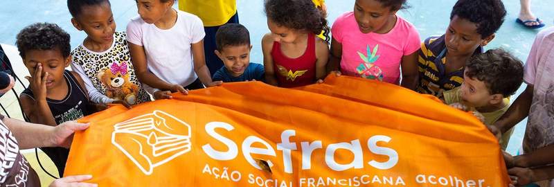 Children and Sefras volunteers holding a banner during an event